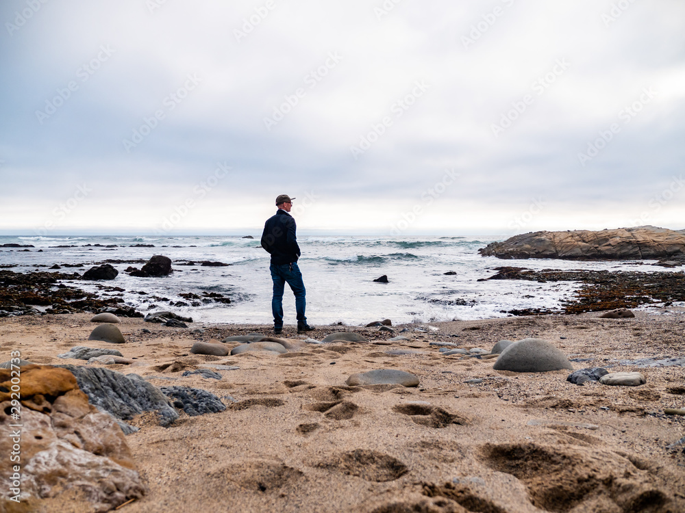 Man on beach looking out towards ocean