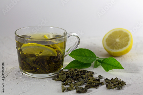 cop of green tea with lemon and leaves on white background