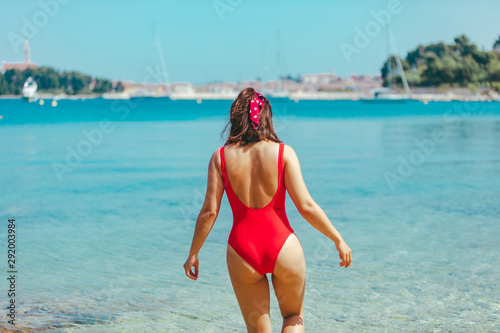 sexy woman in red swimsuit walking into blue clear sea water © phpetrunina14