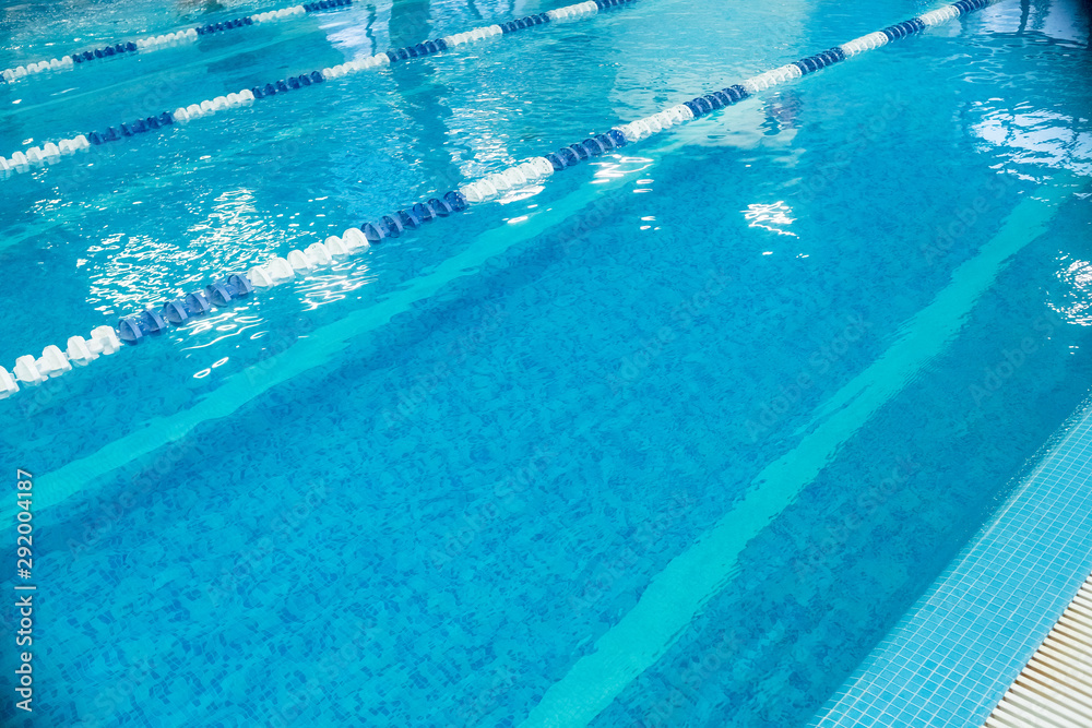 Empty lanes in a swimming pool.Indoor big blue swimming pool interior in modern minimalism style.Lanes of a competition. Healthy life, active sport