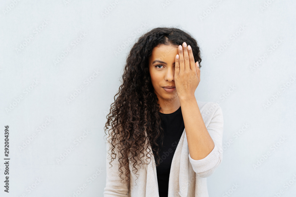 Young African woman covering an eye with a hand Young African woman covering an eye with a hand