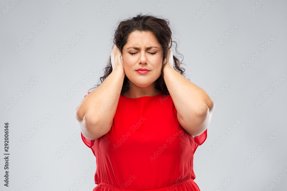 noise, stress and people concept - woman in red dress with closed eyes closing her ears by hands over grey background noise, stress and people concept - woman in red dress with closed eyes closing her ears by hands over grey background