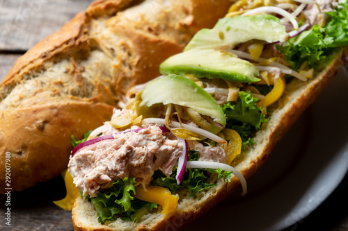Tuna sub sandwich in rustic baguette with avocado, olives and sprouts