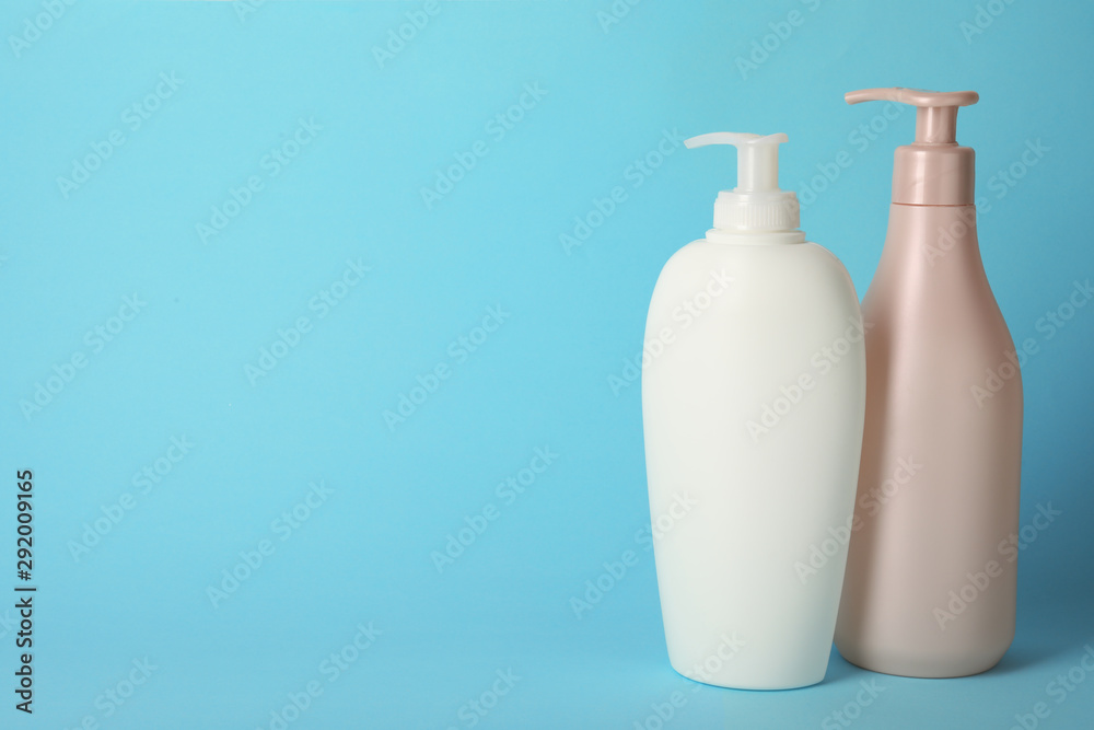 Bottles with hair care cosmetics on light blue background