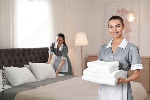 Chambermaid with stack of fresh towels in hotel room. Space for text photo