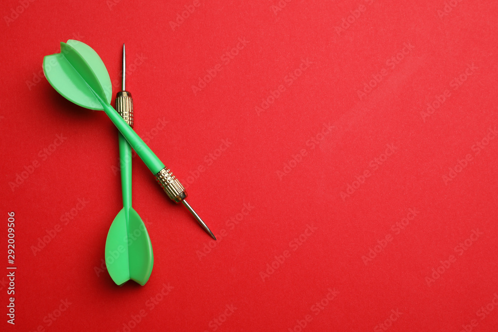 Green dart arrows on red background, flat lay with space for text Green dart arrows on red background, flat lay with space for text