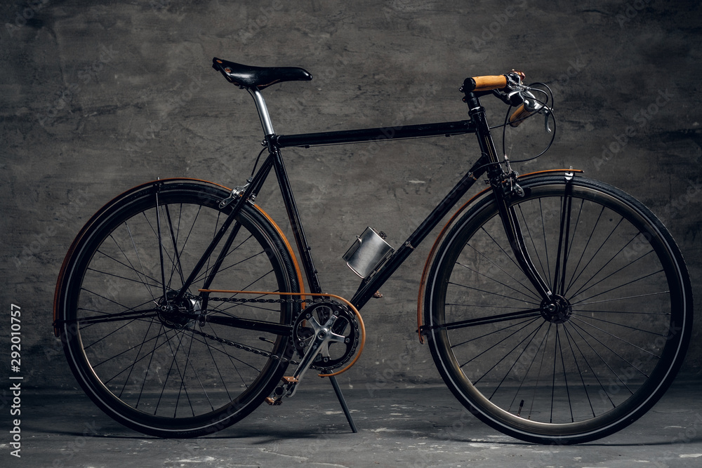 Black retro bicycle is parked at photo studio on the dark background.