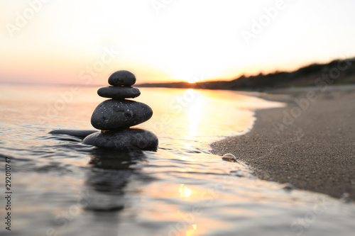 Dark stones on sand near sea at sunset  space for text. Zen concept