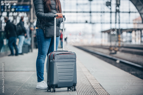 Pretty young woman with luggage waiting at the traint station for her train, transportation concept photo