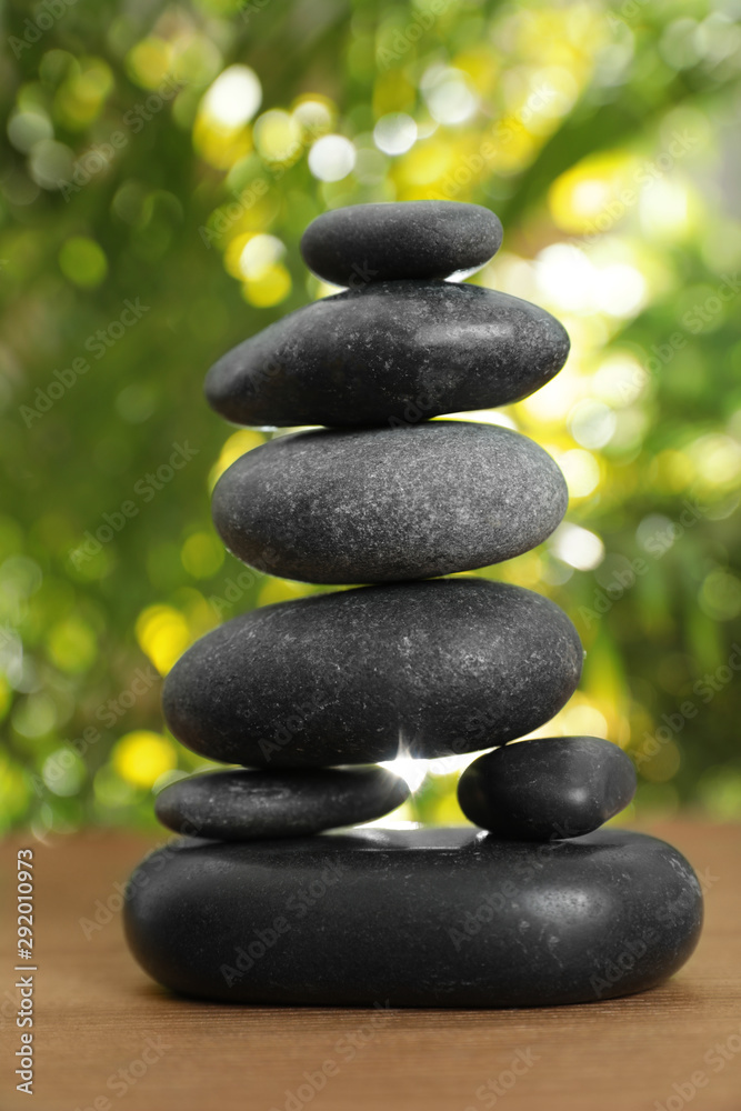 Stack of stones on wooden table against blurred green background, closeup. Zen concept Stack of stones on wooden table against blurred green background, closeup. Zen concept