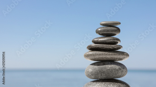 Stack of stones against blurred seascape, space for text. Zen concept