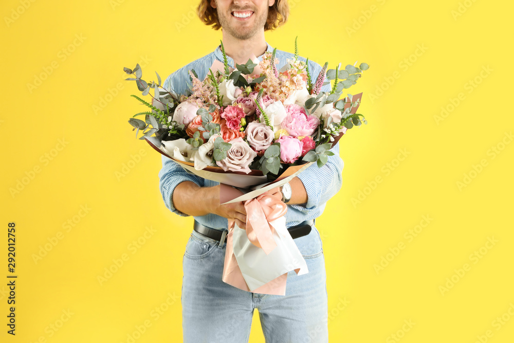 Man holding beautiful flower bouquet on yellow background, closeup view Man holding beautiful flower bouquet on yellow background, closeup view