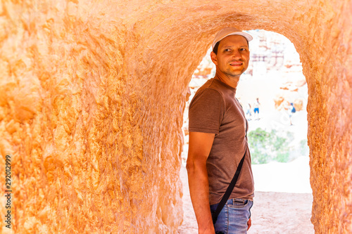 Man tourist person standing in tunnel with orange color at Queens Garden Navajo Loop trail at Bryce Canyon National Park in Utah © Kristina Blokhin