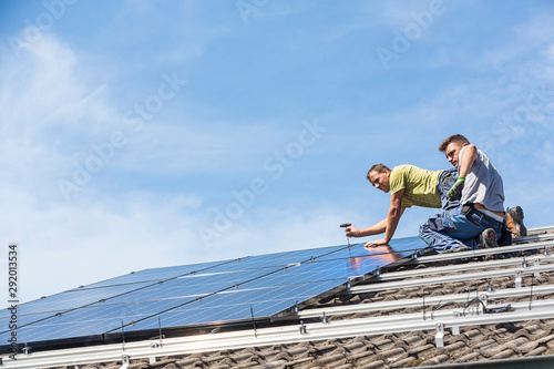 Installing solar photovoltaic panel system. Solar panel technician installing solar panels on roof. Alternative energy ecological concept.