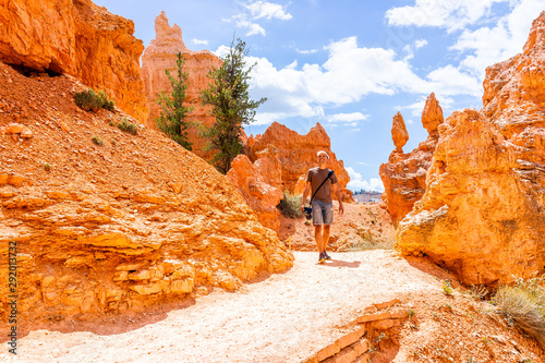 Man tourist person walking by orange color formations at Queens Garden Navajo Loop trail at Bryce Canyon National Park in Utah photo