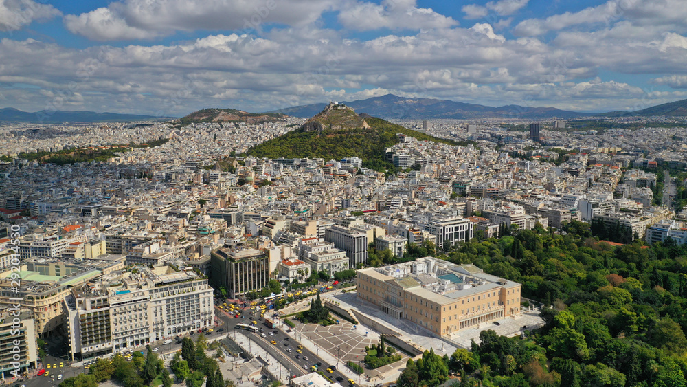 Aerial photo of famous Greek Parliament building in Syntagma square and Lycabettus hill at the background with beautiful clouds and deep blue sky, Athens, Attica, Greece