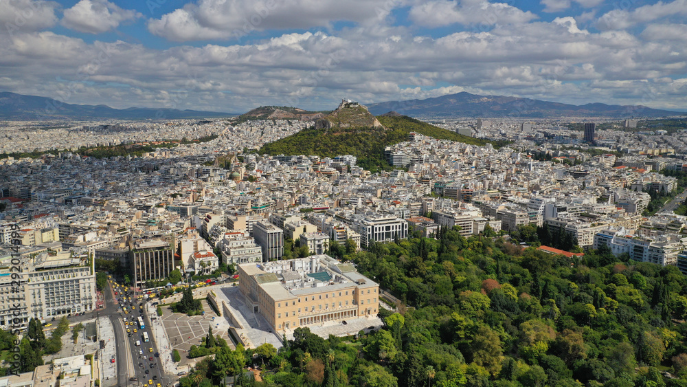 Aerial photo of famous Greek Parliament building in Syntagma square and Lycabettus hill at the background with beautiful clouds and deep blue sky, Athens, Attica, Greece
