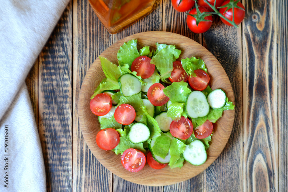 Spring or summer salad with fresh vegetables, cherry tomatoes and cucumbers in a wooden plate on a wooden background Healthy food concept Spring or summer salad with fresh vegetables, cherry tomatoes and cucumbers in a wooden plate on a wooden background Healthy food concept