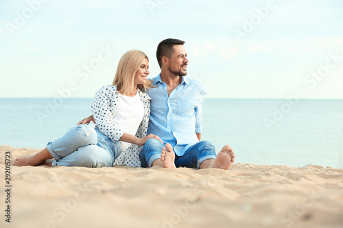 Happy romantic couple spending time together on beach, space for text