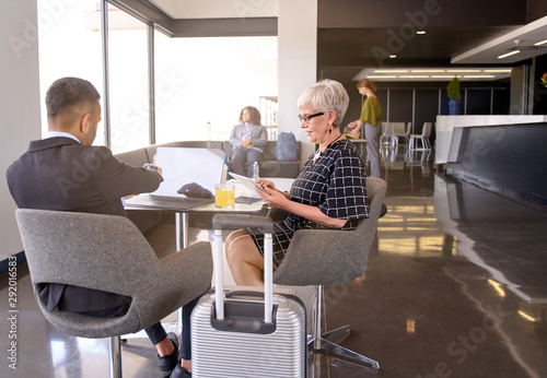 Smiling diverse colleagues sitting in modern airport lounge with baggage developping business ideas together
