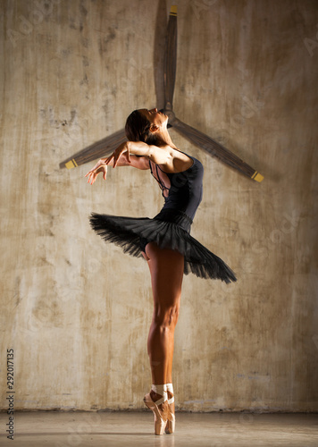 Young beautiful ballerina in black ballet tutu posing in dark studio