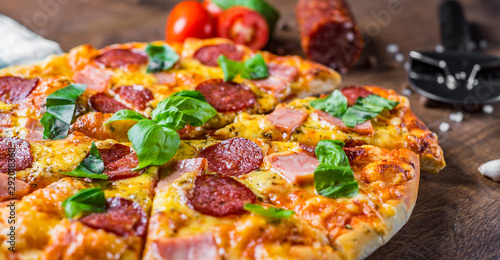 Pepperoni Pizza with Mozzarella cheese, salami, ham, Spices and Fresh basil. Italian pizza on wooden table background