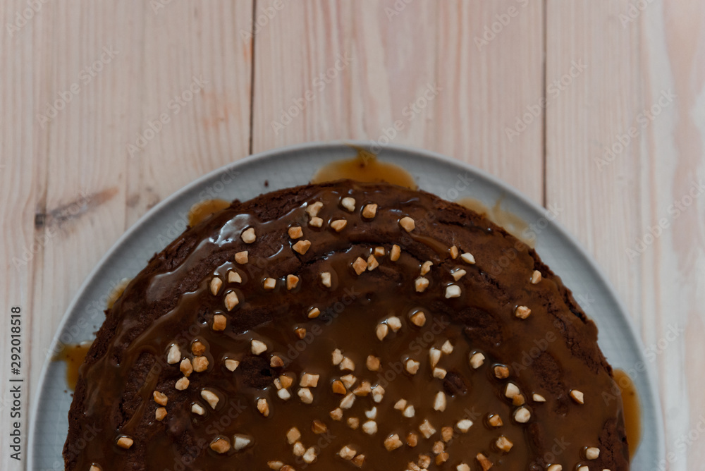 Chocolate cake with nuts. Top view delicious dark chocolate cake on the wood table. A biscuit cake is sprinkled with walnut with chocolate cream. Closeup Chocolate cake with nuts. Top view delicious dark chocolate cake on the wood table. A biscuit cake is sprinkled with walnut with chocolate cream. Closeup