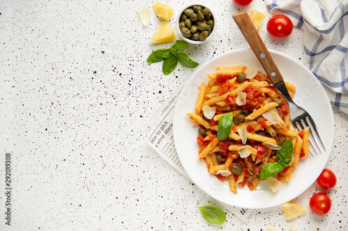 Traditional pasta putanesca with tomato sauce (capers, onions, garlic, anchovies). Tasty Italian food with Parmesan cheese, vegetarian Penne photo
