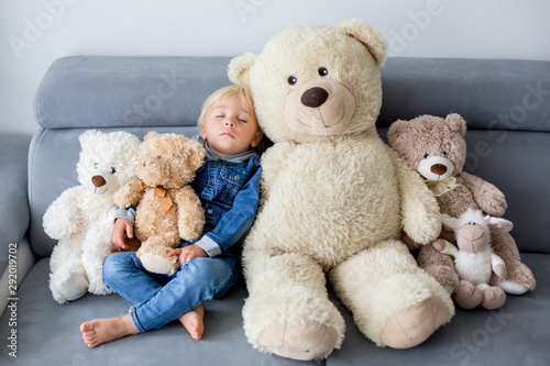 Blond toddler boy, sleeping with many teddy bears in the afternoon