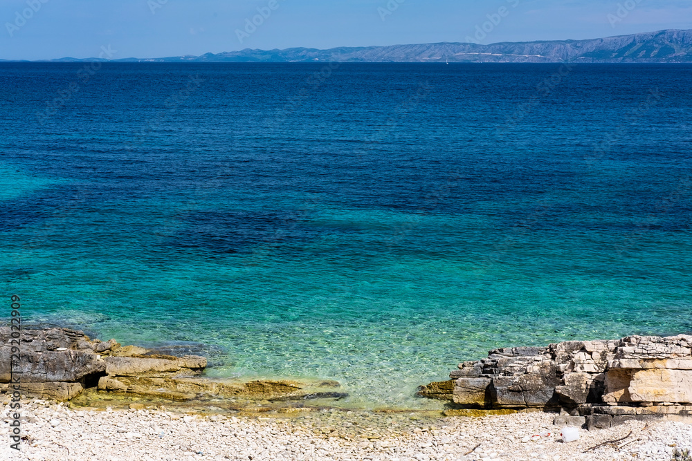 Stone beach on Proizd Island near Korcula Island, Dalmatia, Croatia, blue lagoon, clear sea water and blue sky, one of the most popular beaches in Croatia, nice background image Stone beach on Proizd Island near Korcula Island, Dalmatia, Croatia, blue lagoon, clear sea water and blue sky, one of the most popular beaches in Croatia, nice background image