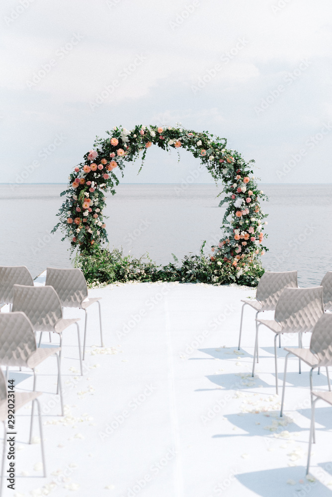 Φωτογραφία The round wedding arch is decorated with a variety of fresh flowers and greens