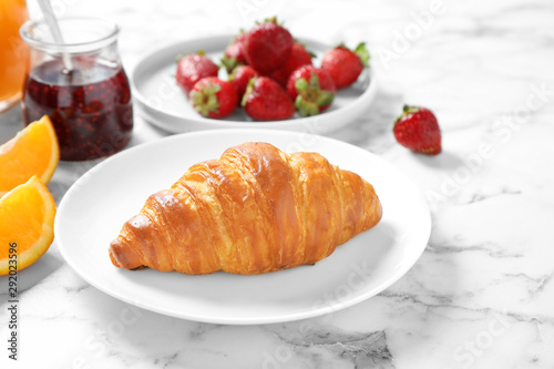 Tasty breakfast with croissant served on white marble table