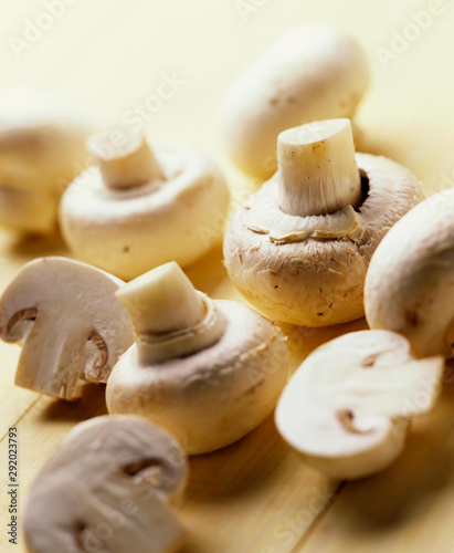 Whole and cut button mushrooms against a light wood background