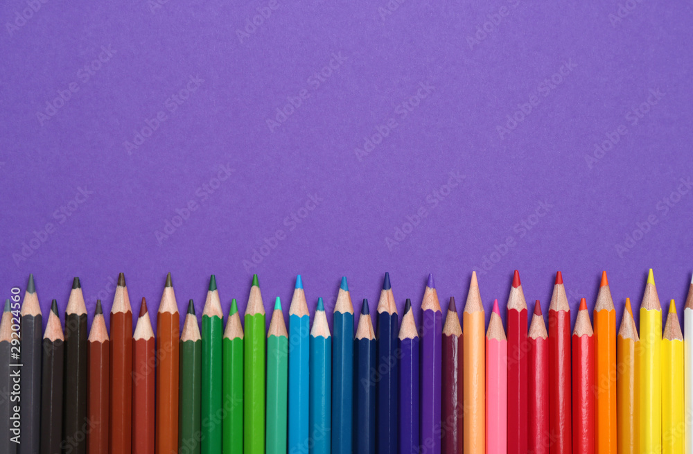 Colorful pencils on purple background, flat lay. Space for text Colorful pencils on purple background, flat lay. Space for text