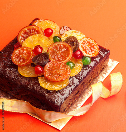 Fruit Cake, decorated with Glaced Fruit on board against red background photo