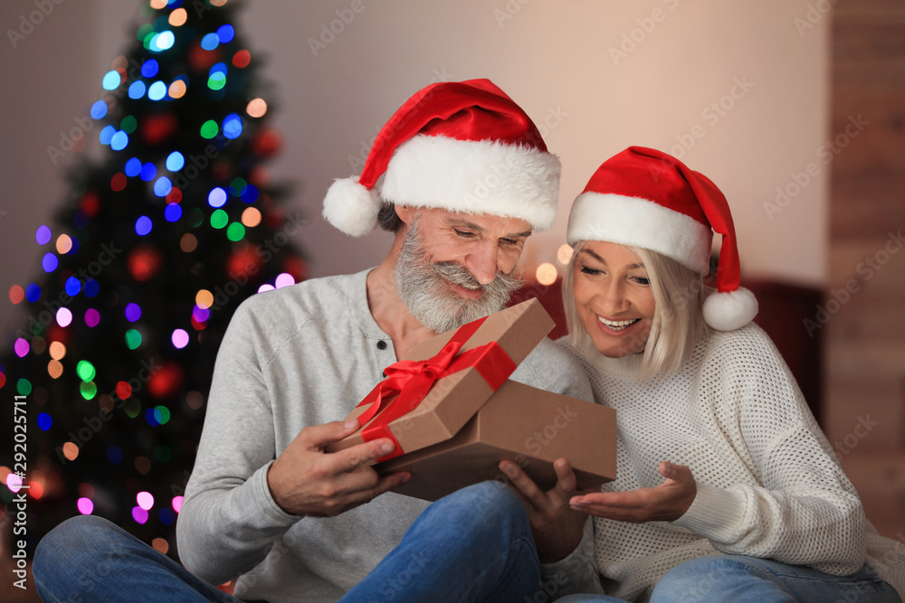 Happy couple opening Christmas gift at home Happy couple opening Christmas gift at home