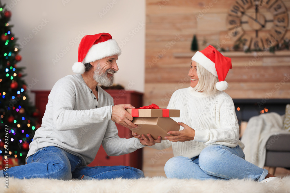 Fototapeta premium Happy couple opening Christmas gift at home