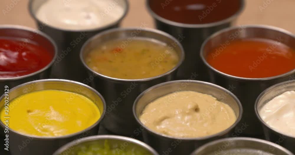 Close-up selection of condiments, dips, and sauces laid out on a slate serving board. Close-up selection of condiments, dips, and sauces laid out on a slate serving board.