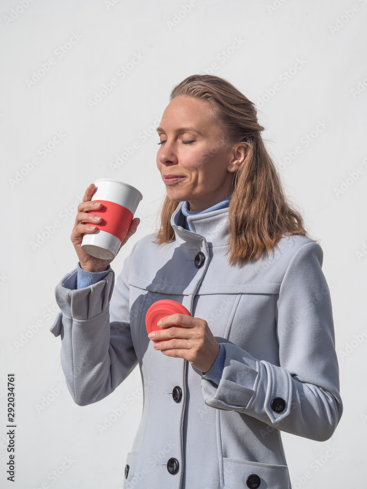 Beautiful middle-aged woman with reusable coffee cup enjoying the autumn sun. Beautiful middle-aged woman with reusable coffee cup enjoying the autumn sun.