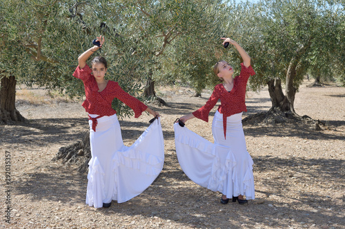 Two girls in a symmetrical position practicing flamenco in an olive grove