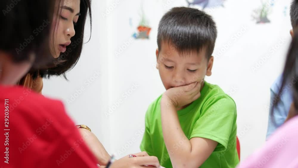 Asian elementary school children are studying in the classroom with an Asian woman teacher.