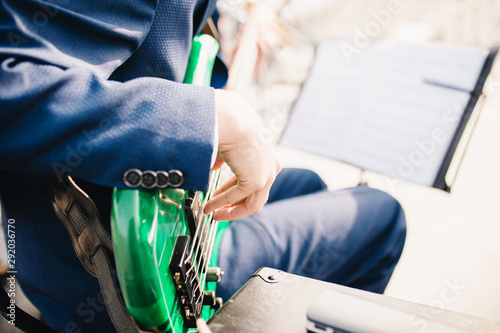 Side view of the fingers of a musician playing bass strings - orchestra guitarist