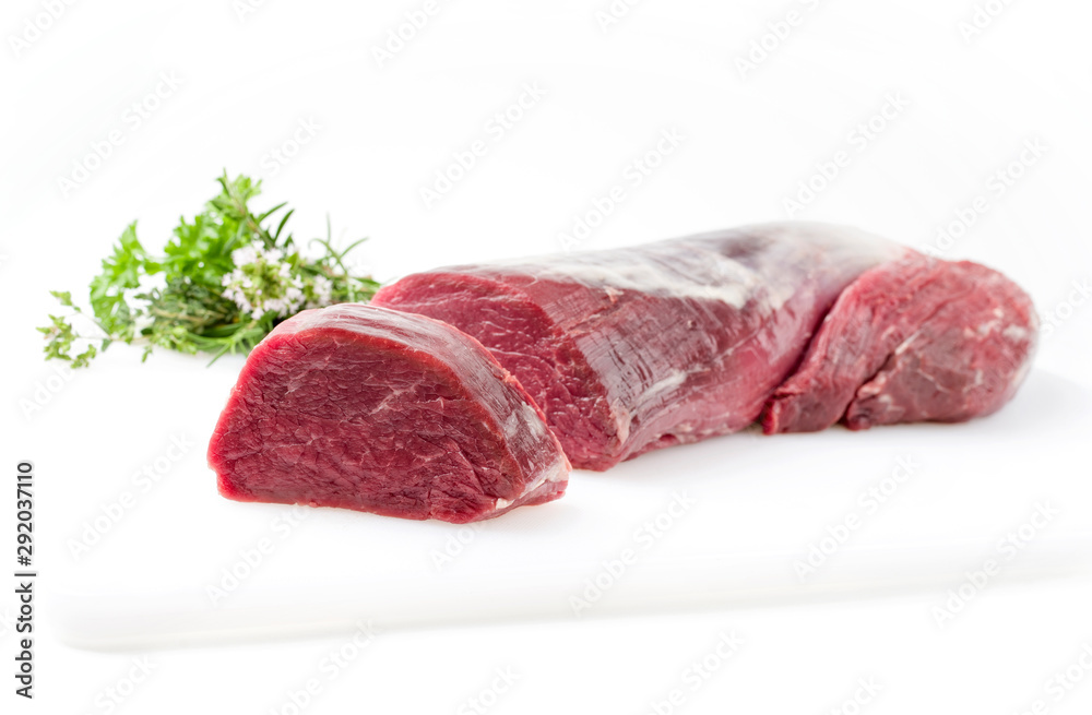Rohes Dry aged Rinderfilet Medaillon Steak natur mit  einem Bouquet Garni Kräuter Straussals closeup auf weissem Hintergrund mit Textfreiraum - freigestellt 