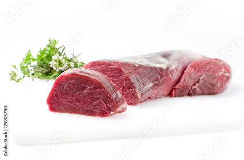 Rohes Dry aged Rinderfilet Medaillon Steak natur mit  einem Bouquet Garni Kräuter Straussals closeup auf weissem Hintergrund mit Textfreiraum - freigestellt 