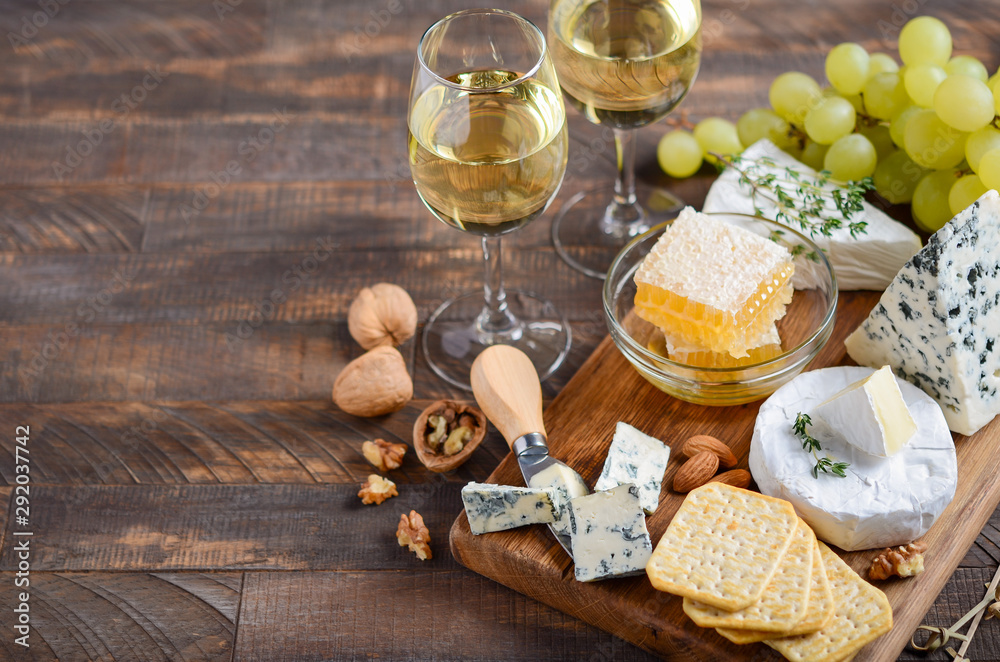 Cheese plate with grapes, crackers, honey, and nuts on a wooden table. Cheese plate with grapes, crackers, honey, and nuts on a wooden table.