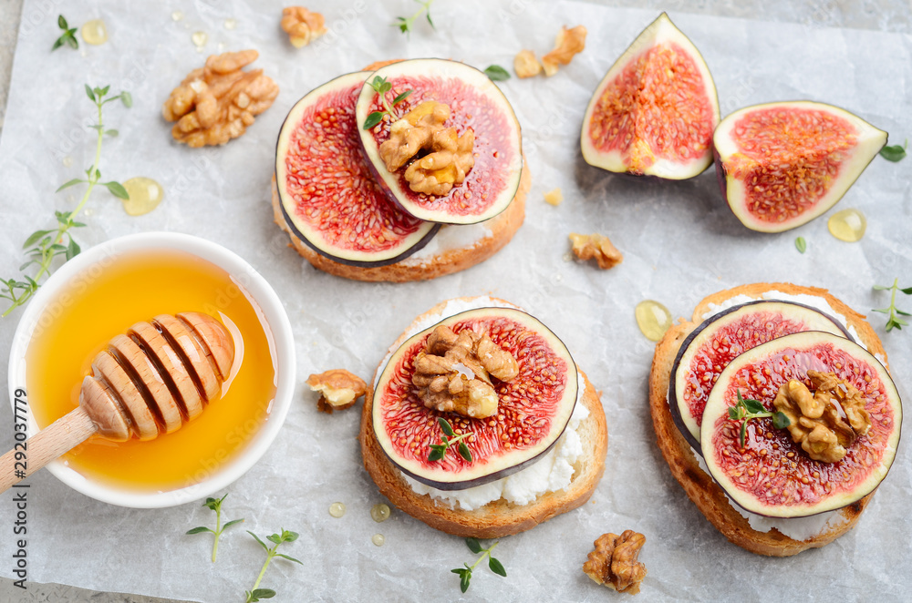 Bruschetta with fresh ricotta cheese, figs, nuts, thyme and honey on gray concrete background. Bruschetta with fresh ricotta cheese, figs, nuts, thyme and honey on gray concrete background.