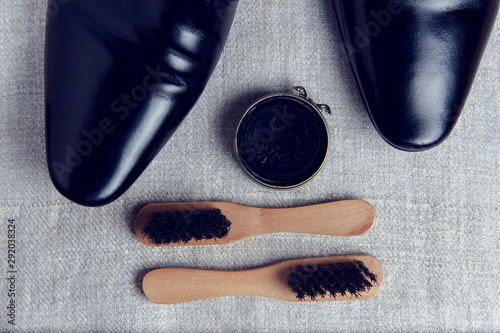 Black classic mens shoes and a set of care for them on a fabric background. Brushes and paste for cleaning shoes.