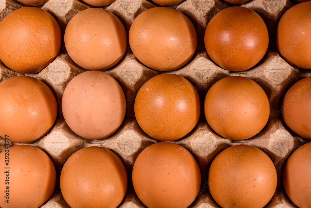 Pile of the hen eggs in paper tray on wooden table. Top view Pile of the hen eggs in paper tray on wooden table. Top view