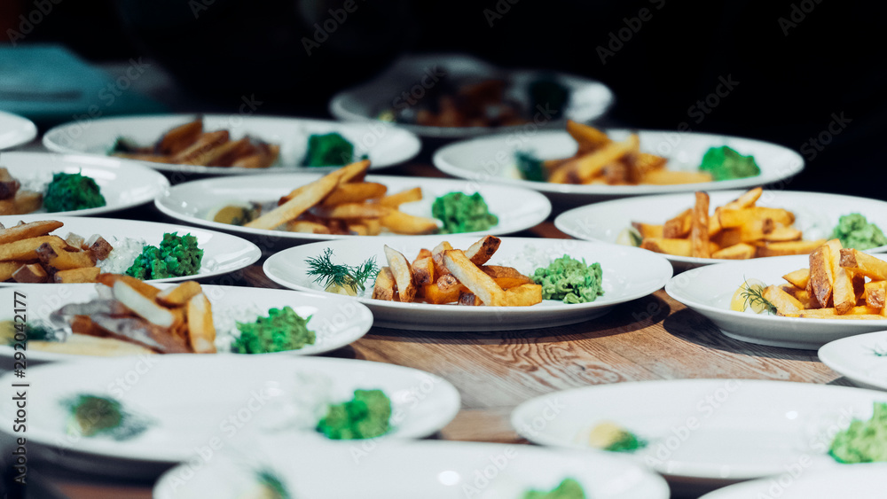 French fries on multiple white plates with dark background. French fries on multiple white plates with dark background.