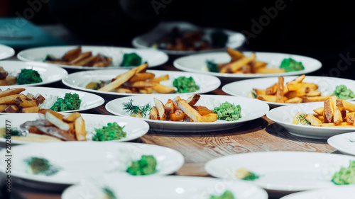 French fries on multiple white plates with dark background.